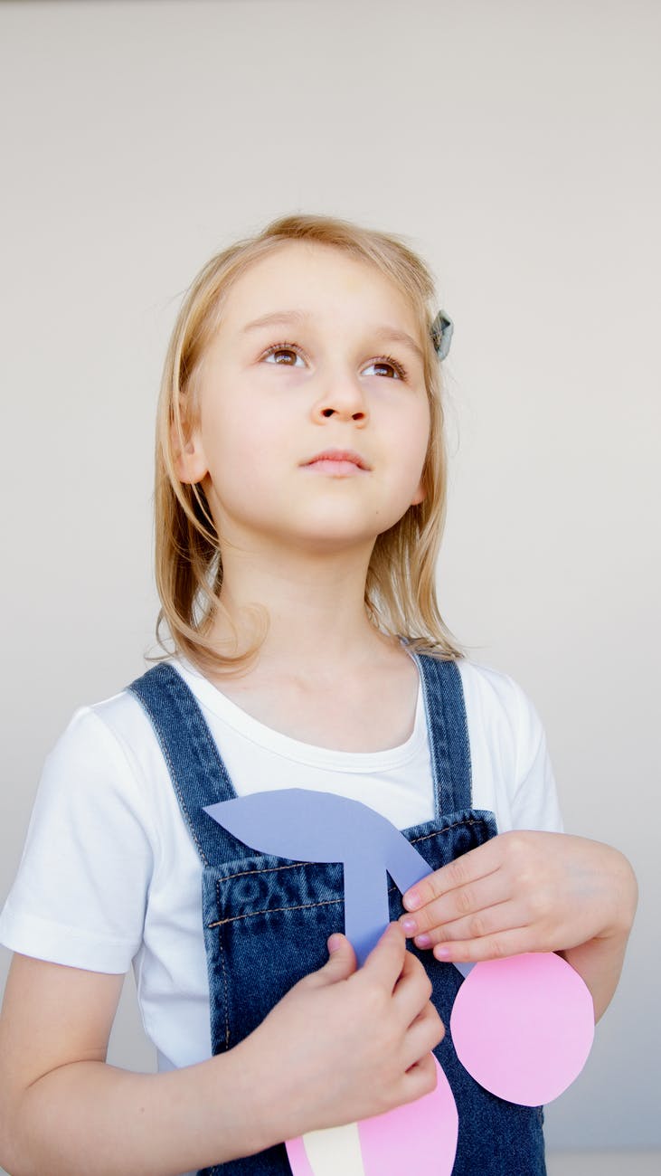 girl looking upwards while holding her artwork